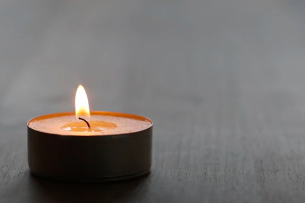 A small candle, alight, on a table